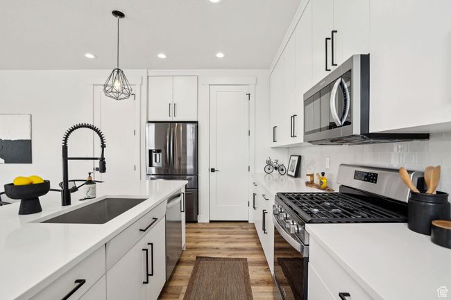 Kitchen featuring light wood-type flooring, a sink, recessed lighting, and appliances with stainless steel finishes | Image 10