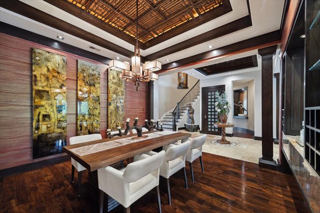 This alluring dining room seamlessly blends refined elegance with artistic expression. A dramatic wood coffered ceiling draws the eye upward, featuring an intricate lattice design and custom Lutron Radio RA2 lighting, which can be tailored to suit any mood or gathering. Thoughtful architectural framing creates a graceful connection to the grand entry and sweeping staircase, allowing the space to feel both expansive and intimate—perfect for sophisticated entertaining. | Image 10