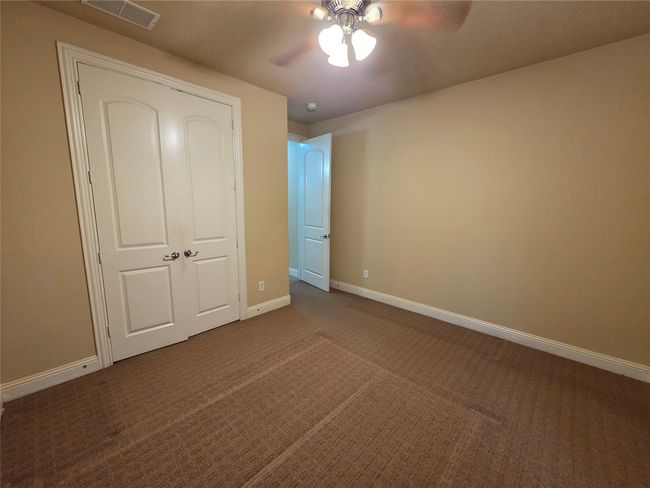 Unfurnished bedroom featuring dark colored carpet and a ceiling fan | Image 5
