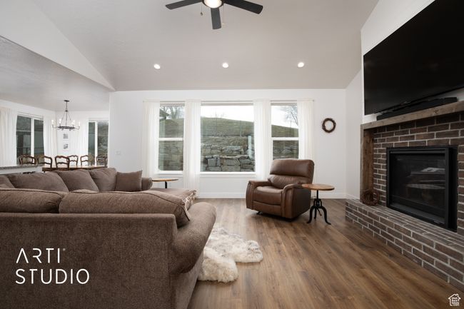 Living room featuring lofted ceiling, hardwood / wood-style floors, ceiling fan with notable chandelier, and a fireplace | Image 8