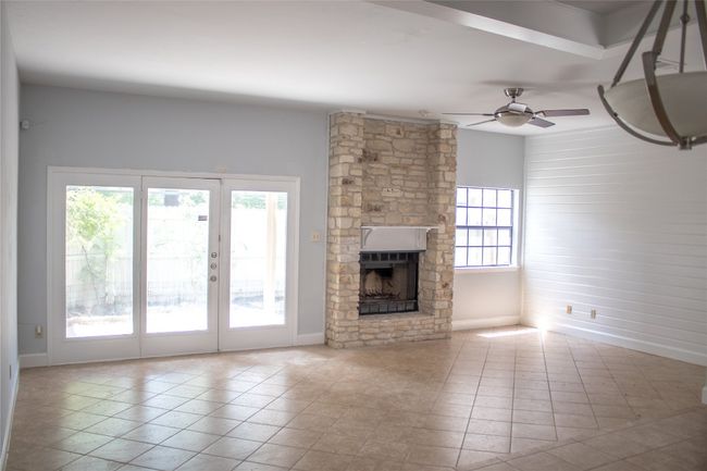 Unfurnished living room featuring ceiling fan, baseboards, tile patterned floors, and a fireplace | Image 10