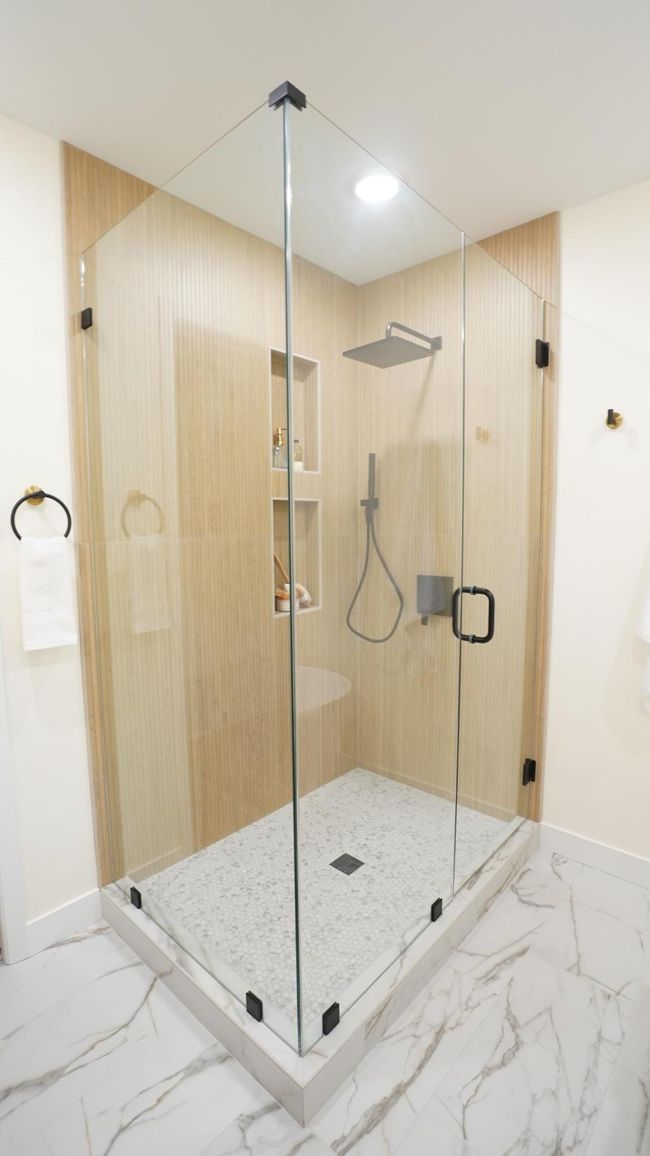 The show-stopping owners' shower is everything luxurious, from the large, two-sided glass surround to the spa-like, modern and sleek shower fixtures. The intricate large format and penny tile is highlighted by the low profile shower curb. | Image 29