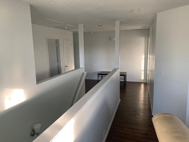 Hallway with a textured ceiling, wood-type flooring, and an upstairs landing | Image 21