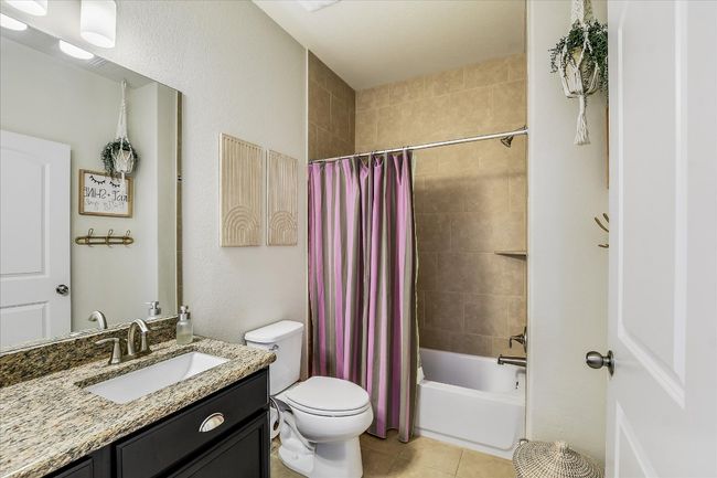 Bathroom featuring toilet, shower / bathtub combination with curtain, vanity, and tile patterned flooring | Image 25
