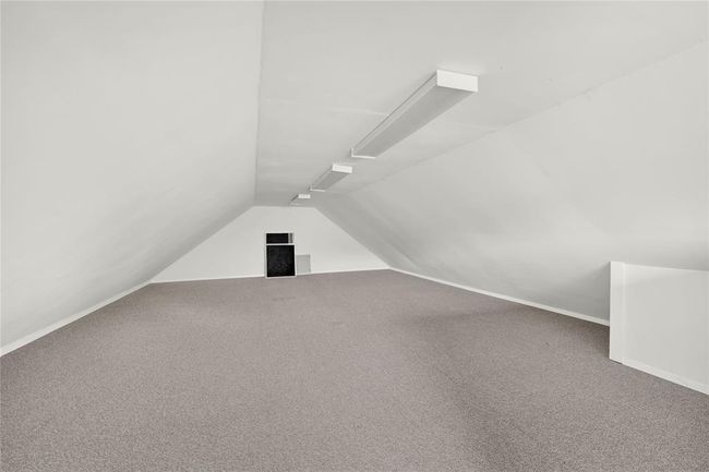 Garage Loft - carpeted space with sloped ceilings and ample overhead lighting, perfect for storage or conversion into a cozy living space. | Image 29