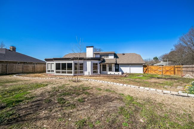 Back of house with a gate, a fenced backyard, a yard, a sunroom, and a chimney | Image 4