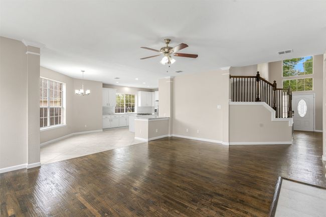 Unfurnished living room featuring ceiling fan with notable chandelier, light wood finished floors, and visible vents | Image 19