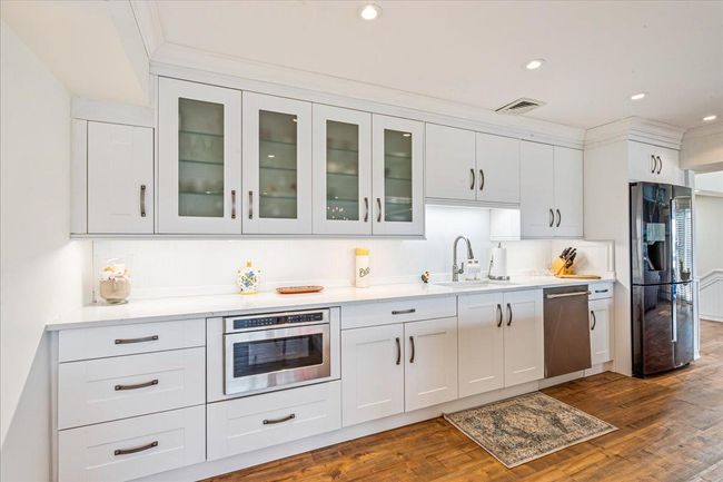 Kitchen with appliances with stainless steel finishes, glass insert cabinets, white cabinetry, dark wood-style flooring, and recessed lighting | Image 8