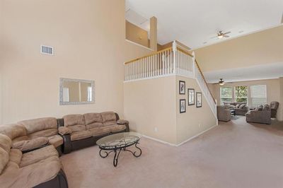 Carpeted living room with a high ceiling and ceiling fan | Image 3