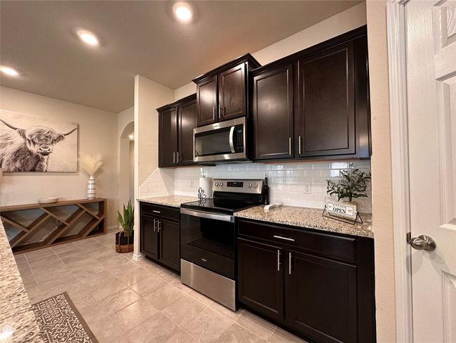 Kitchen featuring appliances with stainless steel finishes, arched walkways, tasteful backsplash, light stone counters, and recessed lighting | Image 23