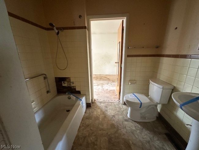 Full bathroom featuring tile flooring, tile walls, toilet, and tiled shower / bath combo | Image 10