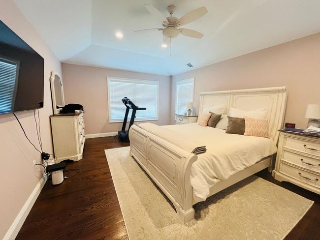 Bedroom with dark wood-type flooring, a tray ceiling, and a ceiling fan | Image 11