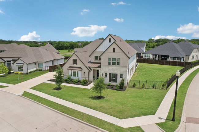 French country style house featuring stone siding, board and batten siding, a standing seam roof, a residential view, and concrete driveway | Image 28
