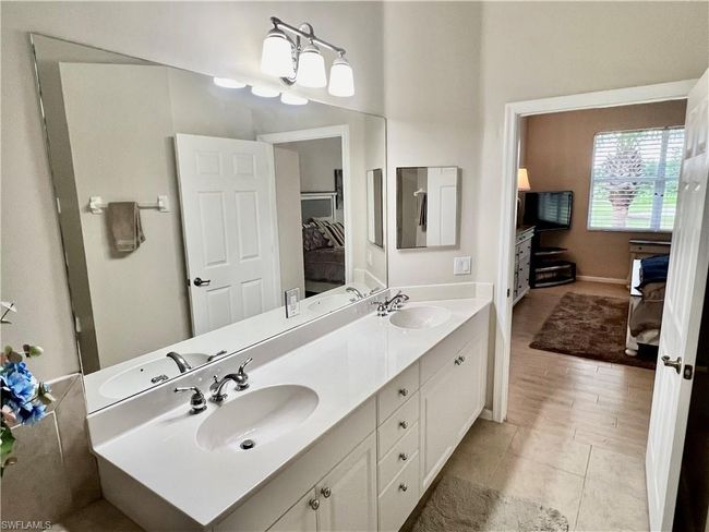 Dual sinks on cultured marble surface with white cabinets | Image 24