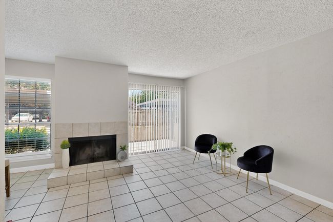 Unfurnished room with a textured ceiling, a tiled fireplace, plenty of natural light, and light tile patterned floors | Image 8
