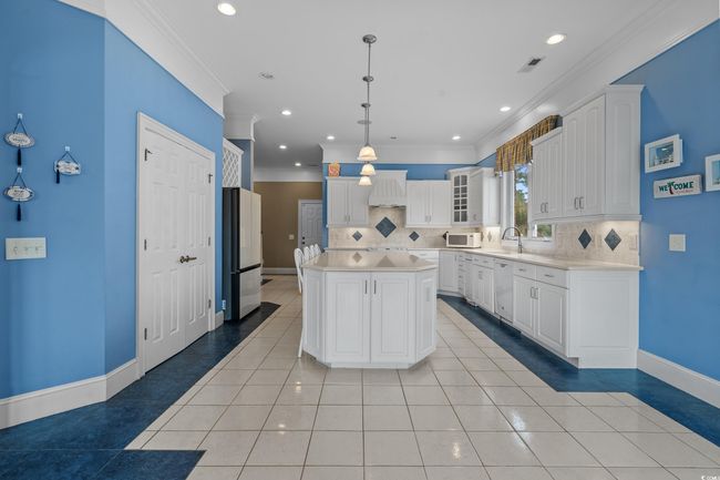 Kitchen with light tile patterned flooring, decorative backsplash, ornamental molding, white appliances, and light countertops | Image 12