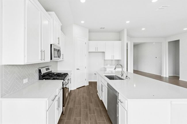 Kitchen featuring stainless steel appliances, a sink, recessed lighting, white cabinetry, and baseboards | Image 7