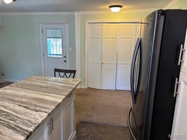 Kitchen with freestanding refrigerator, ornamental molding, dark carpet, baseboards, and light stone counters | Image 19