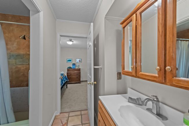 Bathroom with a textured ceiling, connected bathroom, vanity, a shower with curtain, and tile patterned flooring | Image 28