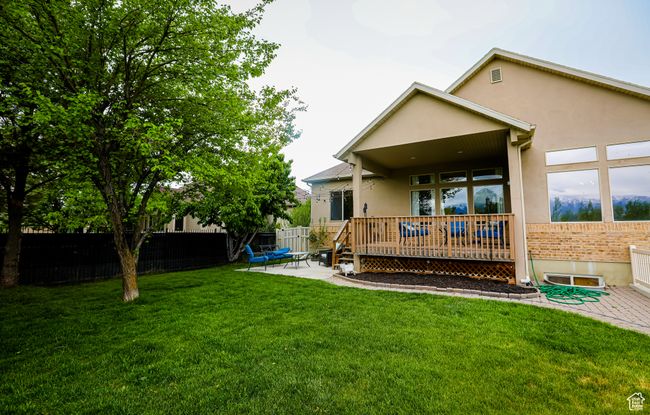 Back of house with stucco siding, a patio, a wooden deck, and brick siding | Image 43