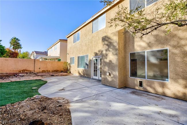 Rear view of house with a patio area, stucco siding, fence, and french doors | Image 47