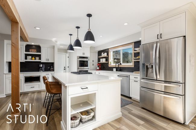 Kitchen featuring white cabinets, appliances with stainless steel finishes, open shelves, and tasteful backsplash | Image 11