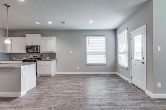 Kitchen with a healthy amount of sunlight, white cabinets, tasteful backsplash, and appliances with stainless steel finishes | Image 9