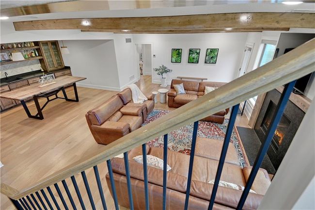 Living area featuring a high end fireplace, light wood finished floors, beamed ceiling, baseboards, and visible vents | Image 40