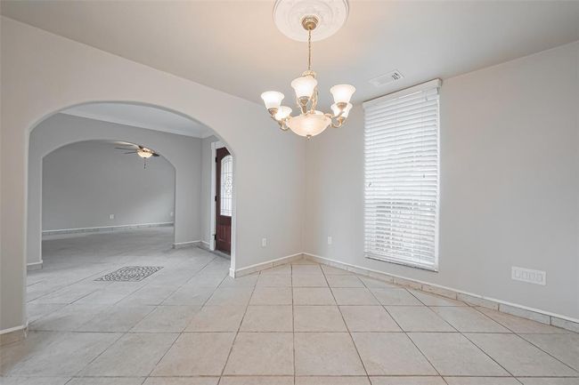 The formal dining room is enhanced by chair rail molding, a classic chandelier, and large windows offering ample natural light. The neutral color palette and tile flooring provide a timeless backdrop for entertaining. | Image 9