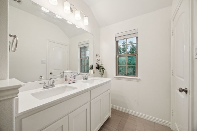 Full bathroom featuring lofted ceiling, baseboards, double vanity, and a sink | Image 17