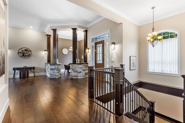 Interior space featuring a healthy amount of sunlight, hardwood / wood-style floors, a notable chandelier, and ornate columns | Image 21