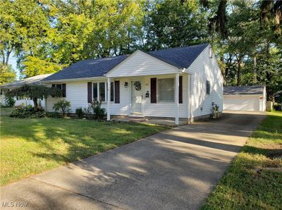 Single story home with an outdoor structure, a garage, covered porch, and a front lawn | Image 1