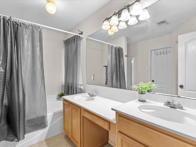 Bathroom with double vanity, shower / bath combination with curtain, and tile patterned floors | Image 20