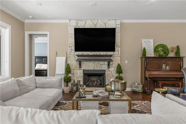 Living room with a stone fireplace, ornamental molding, and wood finished floors | Image 9