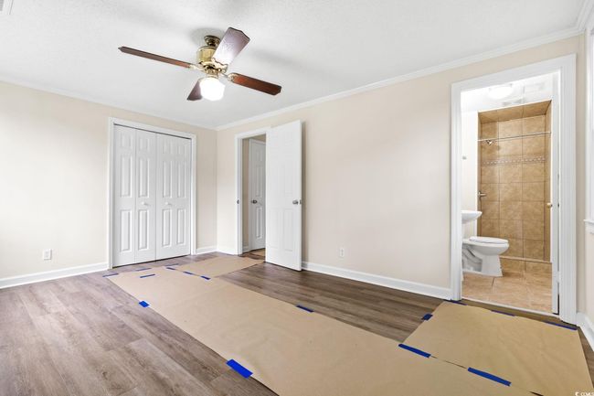 Unfurnished bedroom featuring wood finished floors, baseboards, a closet, ornamental molding, and ensuite bath | Image 29