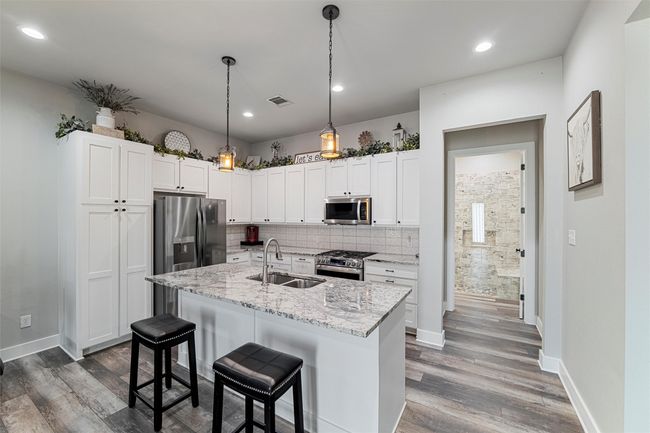 Kitchen featuring tasteful backsplash, stainless steel appliances, a sink, visible vents, and wood finished floors | Image 28