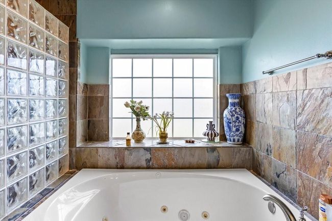 The bathroom’s palette of soft blues, creamy neutrals, and natural stone tiles is inspired by the coast. Blue-and-white porcelain accents, reminiscent of seaside estates, add a touch of timeless charm. Unwind in a luxurious jetted tub to sooth muscles and melt away the stress of the day. | Image 32