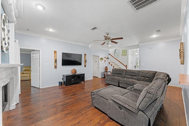 Living room featuring stairs, recessed lighting, a ceiling fan, a fireplace, and wood finished floors | Image 7