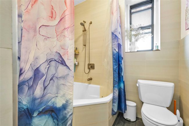 Full bathroom featuring shower / tub combo, toilet, and tile walls | Image 8