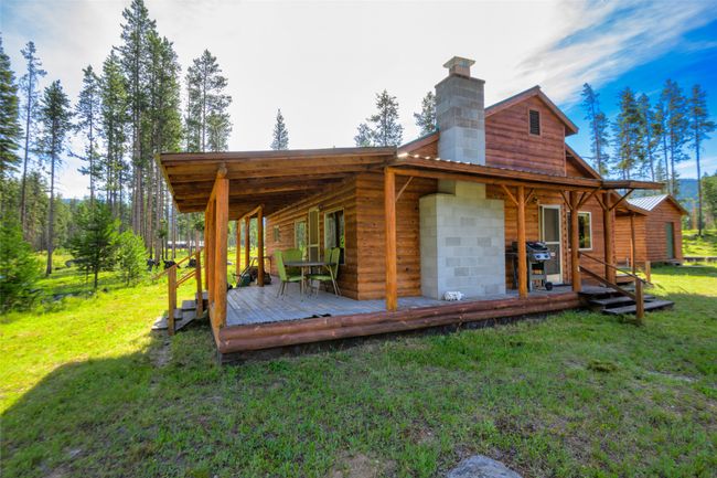 Back of house featuring a yard, a chimney, a wooden deck, and a metal roof | Image 8