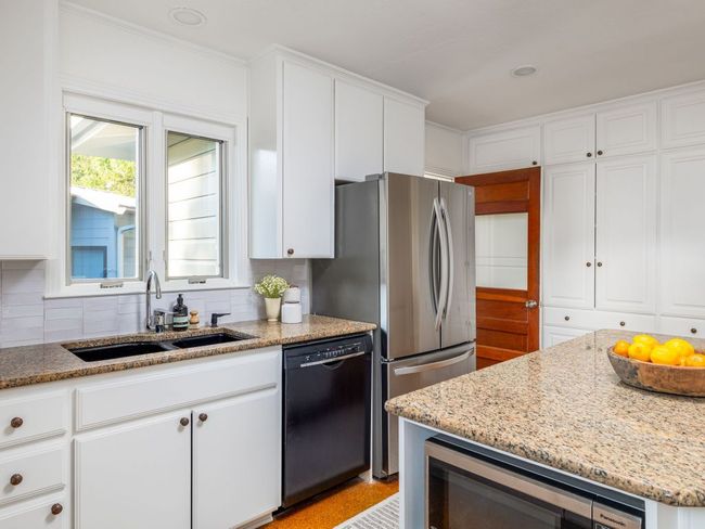 Kitchen featuring white cabinetry, backsplash & light stone counters. | Image 12