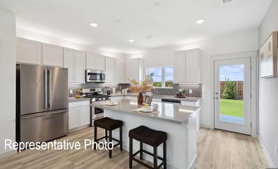 Kitchen with a kitchen bar, white cabinetry, a center island, and stainless steel appliances | Image 2