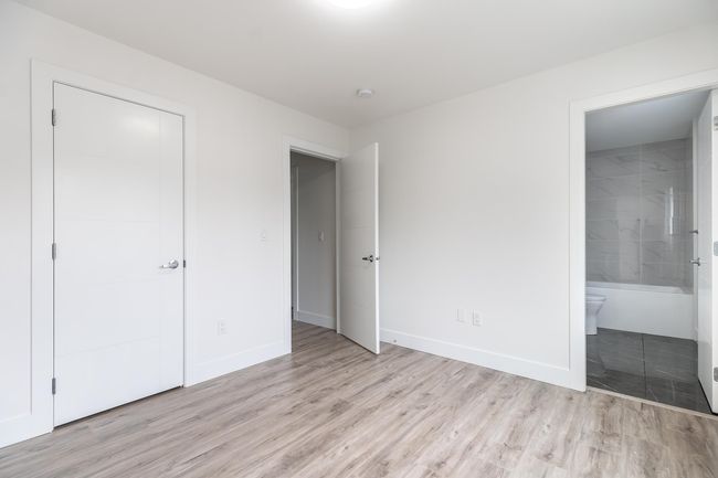 Unfurnished bedroom with light wood-style flooring, baseboards, and ensuite bathroom | Image 26