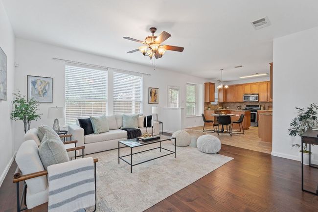 Living area with light wood-style floors, ceiling fan, baseboards, and a chandelier | Image 4
