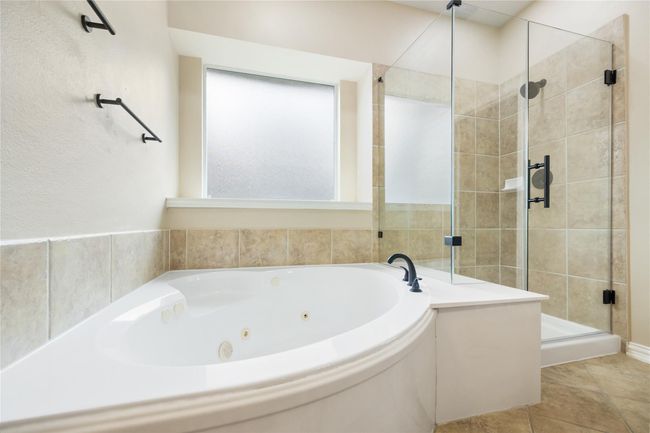 A large frosted window bathes the luxurious jetted tub in natural light while ensuring complete privacy. | Image 23