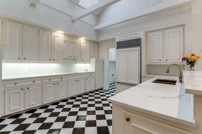 Kitchen featuring a sink, dark flooring, decorative backsplash, light stone countertops, and white cabinets | Image 8
