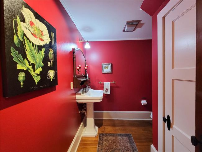 The hall entry boasts elegant built-in cabinets with leaded glass doors and a stylishly decorated half bath featuring a pedestal sink. | Image 11