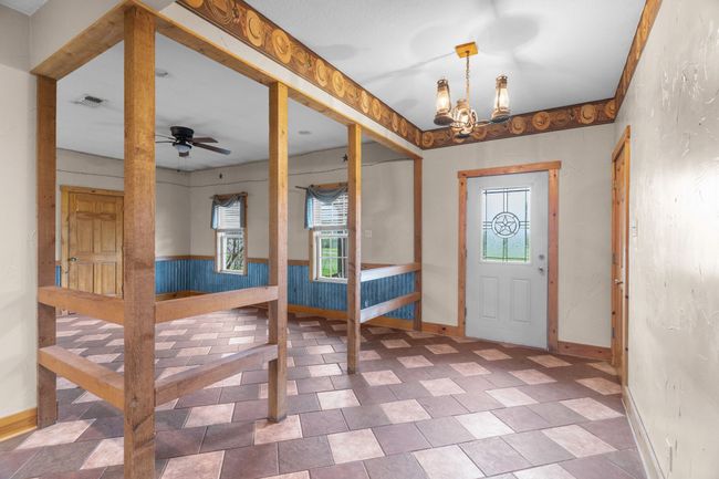 Foyer featuring visible vents, a wainscoted wall, ceiling fan with notable chandelier, and a healthy amount of sunlight | Image 11
