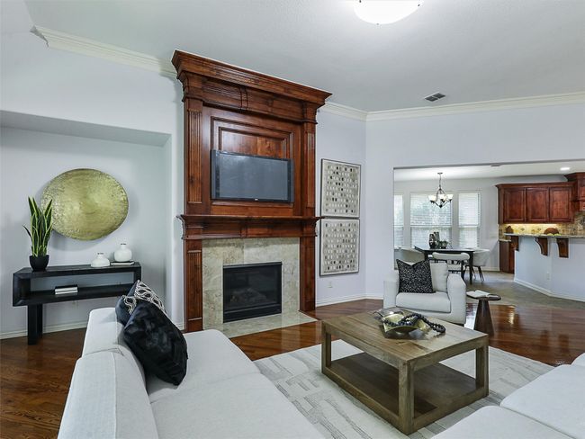 Living room featuring ornamental molding, a chandelier, a tiled fireplace, and wood finished floors | Image 17