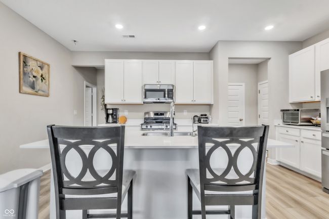 kitchen featuring visible vents, a sink, appliances with stainless steel finishes, a kitchen breakfast bar, and light wood finished floors | Image 11